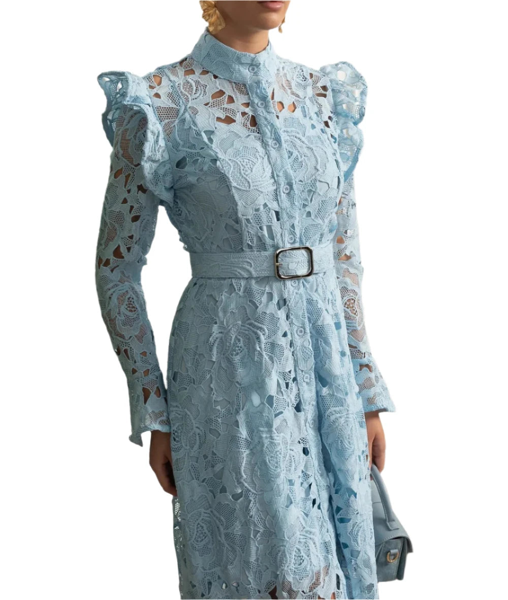 Woman wearing a light blue lace dress with a belt in an elegant interior setting.