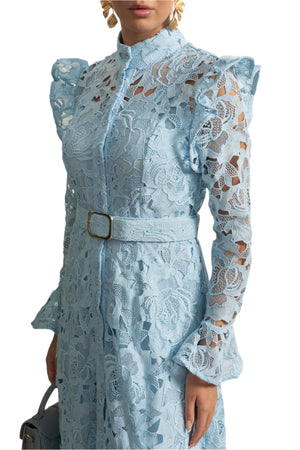 Light blue lace dress with a belt against a decorative wall.