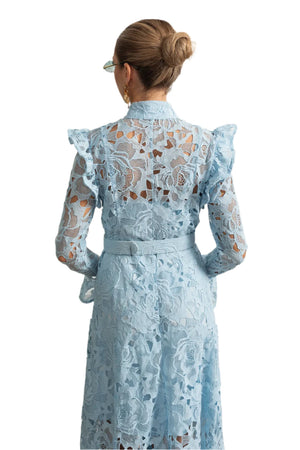 Woman wearing a light blue lace dress in an elegant room.