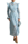 Woman in a light blue lace dress standing in a room with decorative elements.