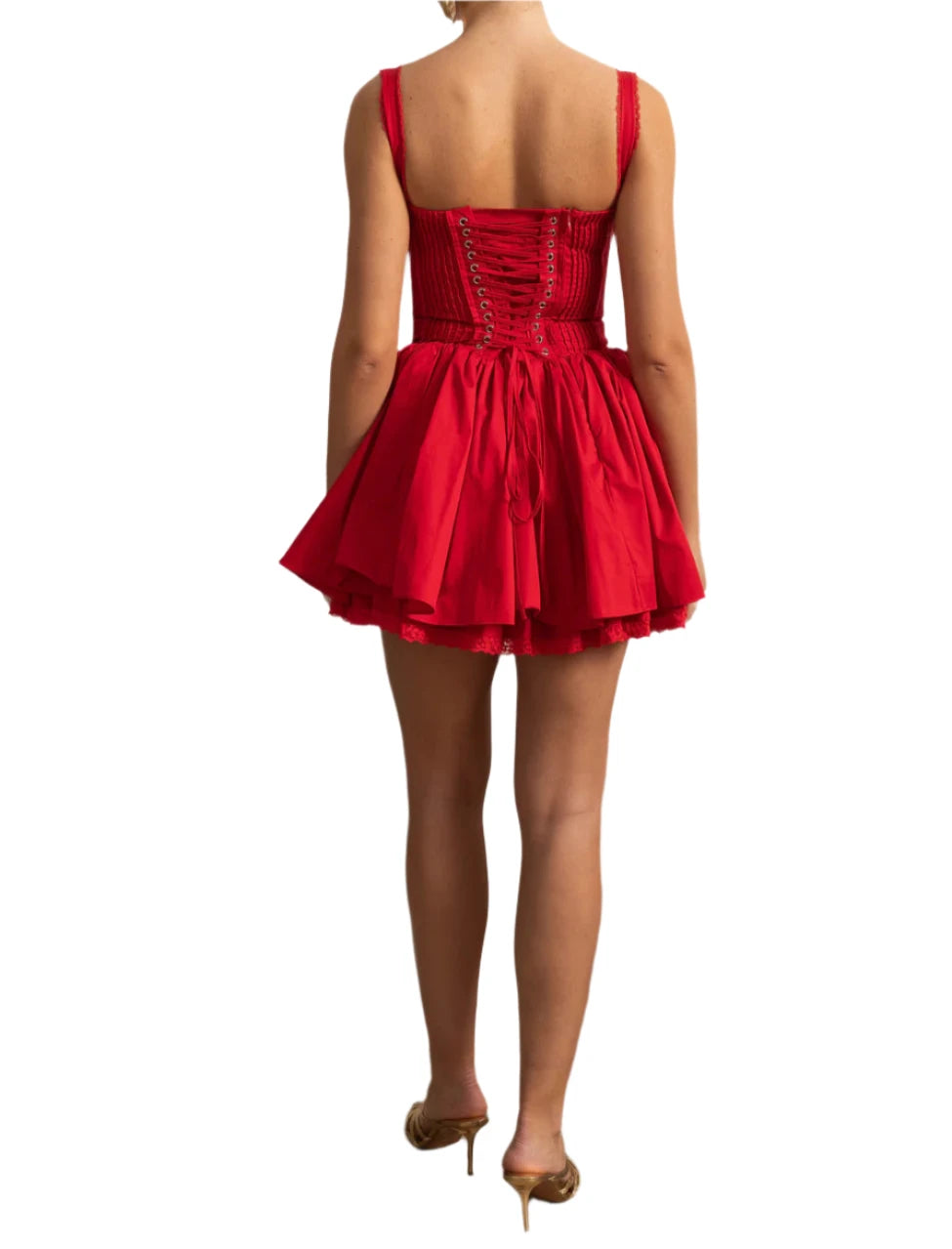 Woman wearing a red dress in a room with decorative wall and plant.