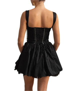 Woman wearing a black dress with a corset back in an elegant room.