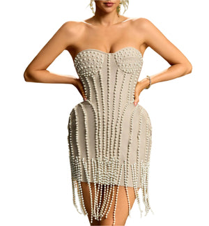 Woman wearing a strapless dress with pearl embellishments against a gradient background
