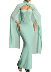 Mint green strapless dress with a flowing cape on a gradient background