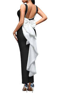Woman wearing a black dress with a white bow on a gray background