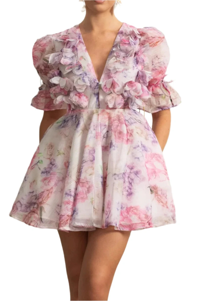 Woman wearing a floral dress in a decorative room with white walls and greenery.