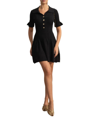 Woman wearing a black dress with buttons in an elegant room.