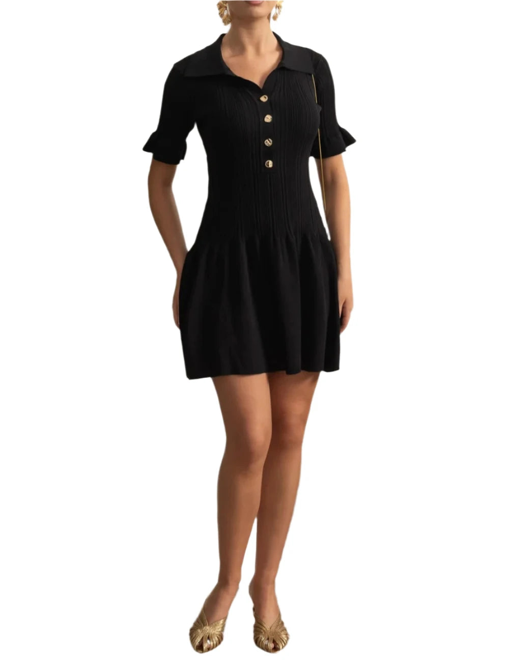 Woman wearing a black dress standing in a room with decorative wall and plant.