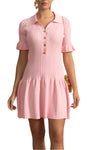 Woman wearing a pink dress with a white wall and decorative elements in the background