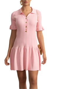Woman wearing a pink dress with a white wall and decorative elements in the background