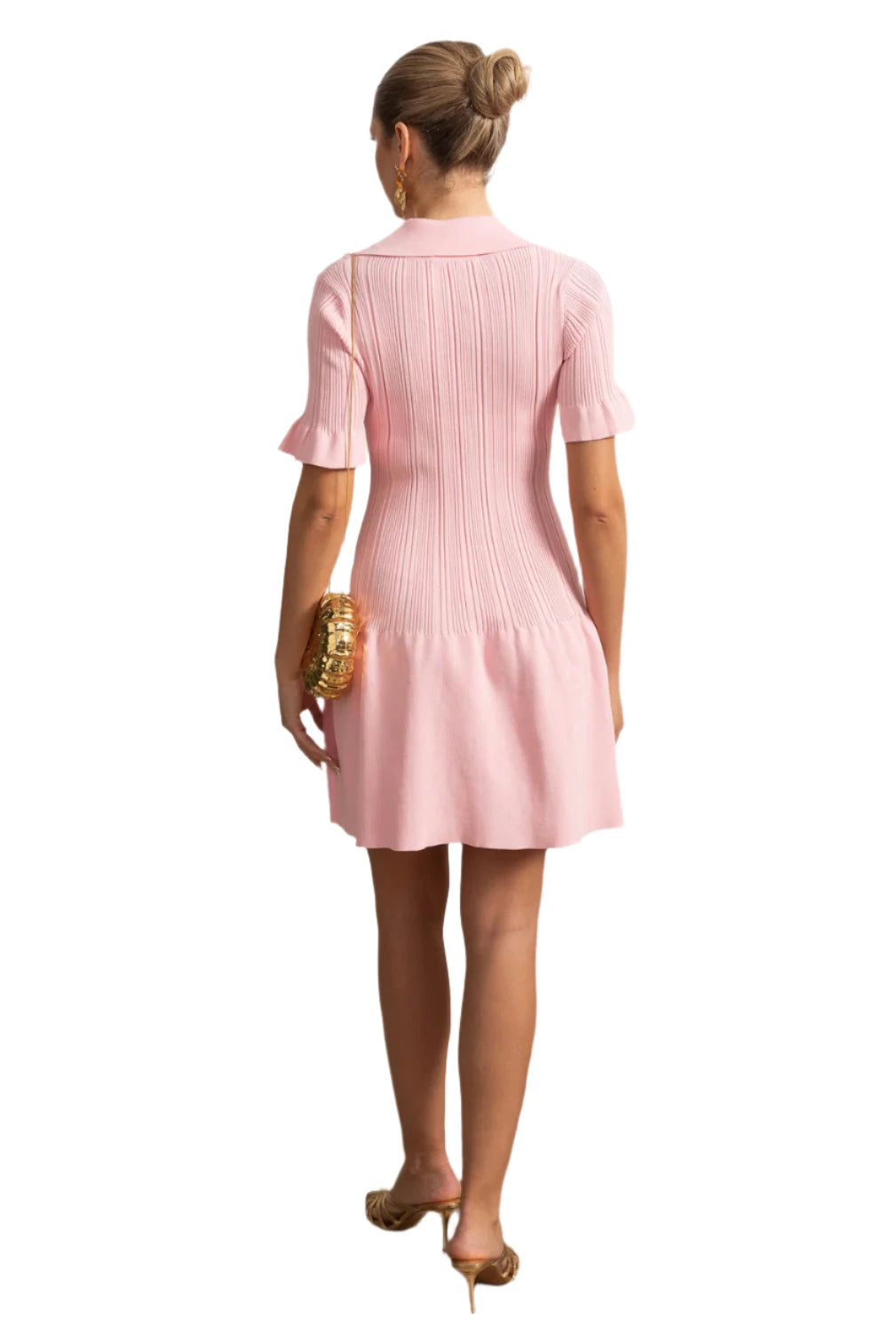 Woman wearing a pink dress standing in a room with decorative elements.