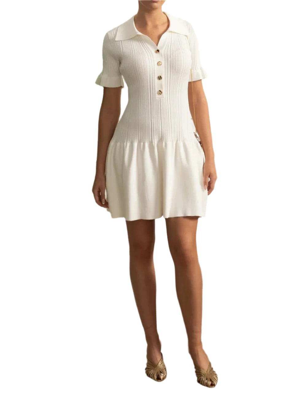 Woman wearing a white dress standing in a room with decorative wall and plant.